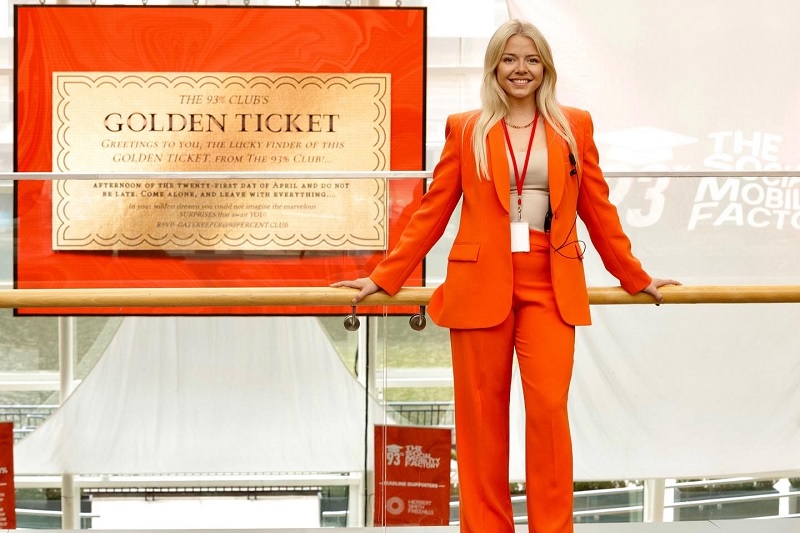 Sophie Pender wears an orange suit and smiles to camera