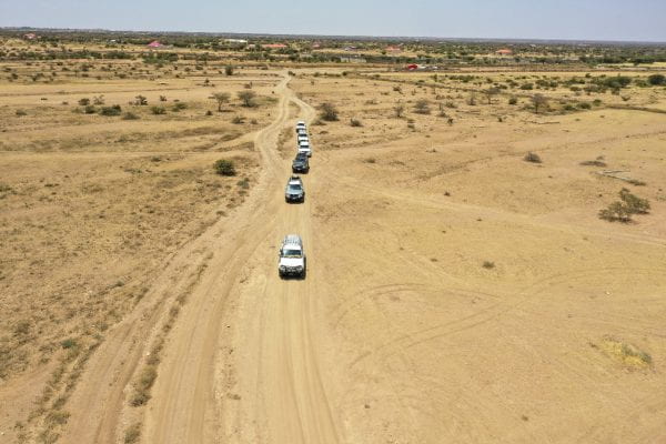 A line of cars drives through the desert.